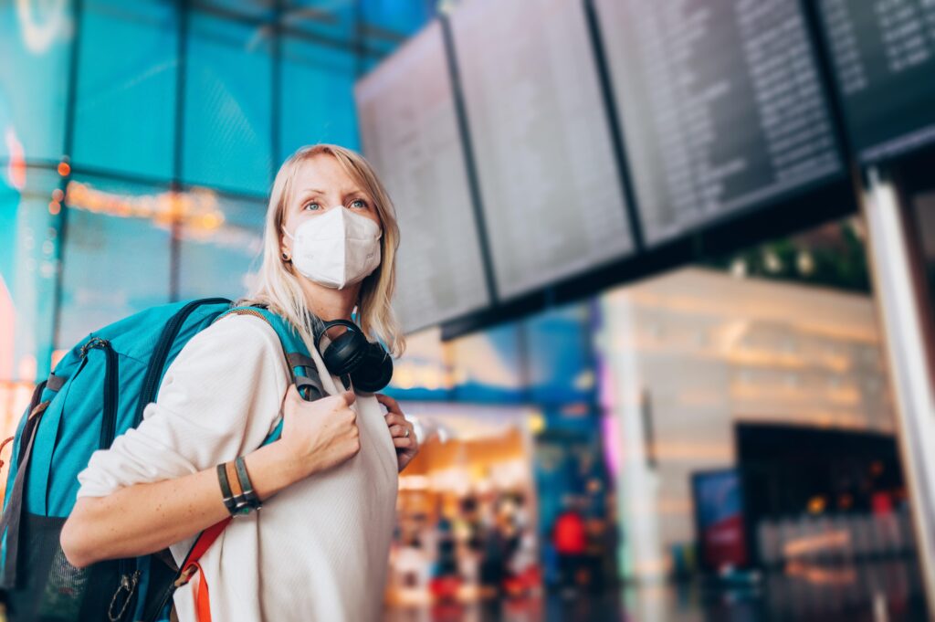 A woman in a mask at an airport looking alert, in reference to security awareness.