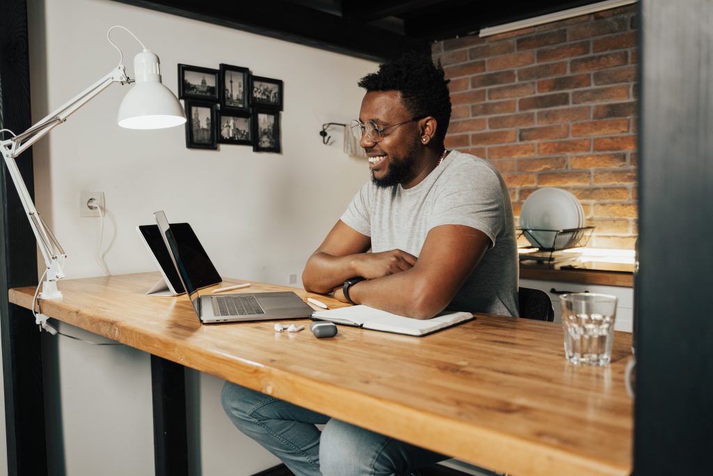 a smiling man takes an onboarding program for his new job from home.
