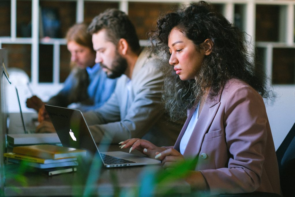 three coworkers in an office space work on different learning and development programs